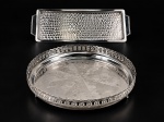 METAL INOX, duas (2) peças confeccionadas em aço inox, sendo; A) ART PRATA, 1 bandeja redonda com galeria em elementos vazados, centro com decoração floral e frisos torcidos, apoiado sobre 3 pés, medindo 7,5x34cm e B) GAZOLA INOX, 1 travessa para rocambole com decoração rodinada, medindo 44x16cm.