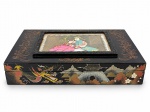 DIVERSOS, uma (1) caixa koreana para tabaco, em madeira laqueada na cor preta, decorada com motivos asiáticos policromados, incluindo dragão, paisagem, flores e arquitetura oriental. Tampa com painel central figurativo representando casal em trajes orientais. Interior revestido em tecido vermelho, com divisórias e caixa musical, compartimentos e recipiente metálico tipo cinzeiro, acompanhada de pequenos acessórios. Apresenta sinais de uso, medindo 6x30,5x18,5cm.
