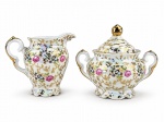 PORCELANA SCHMIDT, duas (2) peças, sendo: A) 1 açucareiro, medindo 11x12x7,5cm e B) 1 cremeira, medindo 9,5x11x6cm, confeccionados em porcelana furtacor com rica decoração floral em policromia e em vasta douração.