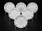 PORCELANAS, seis (6) pratos para pão confeccionados em porcelana na tonalidade branca, decorado por flores e folhagens em policromia, realces vegetalistas em tom branco e borda em ondulações com filetes salmão, leves falhas no filete, medindo 17,5cm de diâmetro.