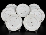 PORCELANAS, sete (7) pratos rasos confeccionados em porcelana na tonalidade branca, decorado por flores e folhagens em policromia com borda filetada a ouro, apresentando falhas na pintura e na douração, 1 com fio de cabelo na borda e 1 com pequena falha de fabricação na borda, medindo 24cm.