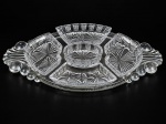 CRISTAIS / VIDROS - (1) Petisqueira em cristal translucido com 4 divisórias e um recipiente para molho , lapidado por caneluras e formas ovais em baixo relevo apoiados sobre bandeja de vidro translucido , medida da petisqueira total : 31 x 19 cm , medida da bandeja : 47 x 23 cm