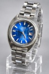 RELÓGIO, um (1) relógio de pulso feminino da marca SEIKO AUTOMATIC, japonês, automático, caixa e pulseira em aço, mostrador azul com marcadores aplicados, ponteiros centrais e calendário às 3 horas. Mostrador marcado SEIKO AUTOMATIC  17 JEWELS  JAPAN 2205T  6010. Caixa, vidro, mostrador e pulseira apresentando riscos, desgastes e sinais do tempo. Peça no estado. Não testado e sem garantia de funcionamento.