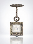 RELÓGIO, um (1) relógio de lapela da marca ORTENA em PRATA 925, de formato retangular, com caixa e alfinete/broche ricamente ornamentados com marcassitas, mostrador claro com algarismos arábicos e ponteiros azulados, unido por elemento articulado decorativo. Peça apresentando sinais de uso, não testado e sem garantia de funcionamento, medindo 5,5x2cm.
