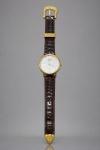 RELÓGIO, um (1) relógio de pulso da marca SUPERATIC, movimento quartz, caixa em metal dourado, mostrador claro com decoração representando repuxados iridescentes e ponteiros dourados. Pulseira em couro marrom texturizado, com fivela, passador e terminal em metal dourado ornamentado com motivos florais em relevo. Tampa traseira em aço, com etiqueta antiga de procedência. Leves sinais de uso, não testado e sem garantia de funcionamento, caixa medindo 4cm.