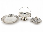 METAL PRATEADO, três (3) peças confeccionadas em metal espessurado a prata com banho novo, sendo: A) 1 pequena fruteira da MERIDIONAL com borda em caneluras vazadas e ondulações, medindo 18cm, B) 1 pequena cesta com cinzelado vegetalista em vazados, alça central articulável e base circular, medindo 14,5x13,5x13,5cm e C) 1 petisqueira com quatro divisórias, alça central fixa, medindo 6x11x11cm.