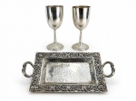 METAL PRATEADO, três (3) peças confeccionadas em metal espessurado a prata, sendo: A) 1 par de taças para vinho da manufatura EBERLE, corpo liso, haste cilíndrica e base em elementos vegetalistas com borda perolada, medindo 17,5x7cm e B) 1 bandeja retangular com decoração martelada, cinzelado por guirlanda floral em relevo e alças vazadas em serpentes, medindo 30,5x18cm.