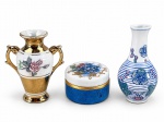 PORCELANAS, três (3) peças confeccionadas em porcelana na tonalidade branca, sendo: A) 1 pequeno vaso ânfora com vasta douração, decorado por flores e folhagens em policromia, alças laterais vazadas, medindo 8x6,5cm, B) 1 pequena caixa porta pilúlas com pintura azul e decoração floral em policromia com realces em douração, medindo 3,5x5cm e C) 1 pequeno vaso balauste com decoração floral e gemétrica em policromia, medindo 9cm.