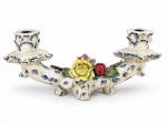 FAIANÇA, um (1) candelabro para duas velas confeccionados em faiança vitrificada na tonalidade creme, decorada por flores e folhagens em relevo e policromia, hastes em arabescos com realces filetados na cor azul, bobeches no feitio de flor, apresentam leves bicados e sinais de craquele, medindo 13x32cm.