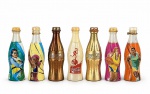 COLECIONISMO, sete (7) garrafas decorativas/promocionais COCA-COLA, confeccionadas em material plástico, em formato clássico da marca, com diferentes acabamentos e estampas, sendo algumas com acabamento metalizado em tons de cobre e dourado e outras com ilustrações esportivas policromada, medindo 8cm.
