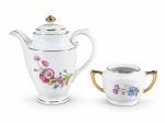 PORCELANA REAL, duas (2) peças confeccionadas em porcelana na tonalidade branca, decorados por flores e folhagens em policromia, filetes e adornos em ouro, sendo; A) 1 bule para café, medindo 17,5x17x7cm e B) 1 açucareiro sem tampa, medindo 7x13x7cm.