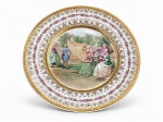 PORCELANA S, um (1) prato decorativo confeccionado em porcelana na tonalidade branca. decorada por guirlanda floral em policromia e douração, borda filetada a dourada decorada por elementos geométricos, centro representando cena galante em policromia, apresentando falhas na douração, medindo 24,5cm.