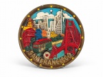 FAIANÇA, um (1) prato decorativo confeccionado em faiança da manufatura KAROL WESTERN, decoração em alto-relevo representando pontos emblemáticos da cidade, entre eles a Golden Gate Bridge, bonde, Transamerica Pyramid e paisagem urbana, circundada por estrelas e inscrição SAN FRANCISCO, possui furo para fixação e guarnição para suspensão em metal, apresenta rachadura, vide foto, medindo 21,5cm.