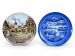 PORCELANAS, dois (2) pratos decorativos confeccionados em porcelana na tonalidade branca, sendo: A) REUTTER, W-GERMANY, 1 prato alusivo à Alemanha  World Showcase, EPCOT Center, com cena arquitetônica em policromia, medindo 19,5cm e B) 1 prato alusivo à cidade de Seattle, EUA, em tons de azul, com vistas e referências locais como Space Needle, Mount Rainier, Kingdome, ferry boat e trolley car, com inscrição Seattle  The Emerald City, medindo 20,5cm.