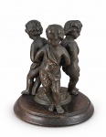 BRONZE, uma (1) base para floreira confeccionada em bronze, representando três puttos com acabamento possivelmente europeu, base circular com cinzelado vegetalista em relevo, apoiada sobre placa redonda em madeira escura, medindo 12x8cm.
