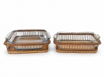 VIDROS, dois (2) pirex em vidro temperado, acompanhadas de suportes/cestos trançados em vime, com alças laterais. Conjuntos destinados ao serviço de mesa e apresentação de alimentos. Apresentam sinais de uso e desgastes nas laterais do vime, quadrangular medindo 7x26x25,5cm e 8x26,5x16cm.
