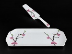 PORCELANAS, conjunto com duas (2) peças para rocambole confeccionada em porcelana na tonalidade branca, decorada por galhos e elementos florais em policromia, sendo: A) 1 travessa para rocambole, medindo 32x14,5cm e B) 1 pá, medindo 25cm de comprimento.