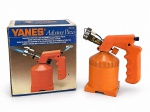 FERRAMENTA, um (1) maçarico portátil YANES Advance Piezo, cód. 4450, com acendimento eletrônico piezoelétrico, corpo em material plástico na cor laranja, reservatório integrado e bico metálico para chama direcionada. Acompanha caixa original, apresentando sinais de uso e armazenamento. Funcionamento não testado, medindo 21x19cm.