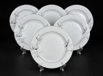 PORCELANA DM BRASIL, seis (6) pratos rasos confeccionados em porcelana na tonalidade branca, decorada por flores e folhagens em monocromia na tonalidade cinza com filetes e realces em prata, medindo 27cm.