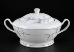 PORCELANA DM BRASIL, uma (1) sopeira confeccionada em porcelana na tonalidade branca, decorada por flores e folhagens em monocromia na tonalidade cinza com filetes e realces em prata, leves falhas na prateação, medindo 16x29x15cm.