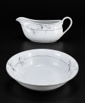 PORCELANA DM BRASIL, duas (2) peças confeccionadas em porcelana na tonalidade branca, decorada por flores e folhagens em monocromia na tonalidade cinza com filetes e realces em prata, leves falhas na prateação, sendo: A) 1 saladeira, medindo 6x23cm e B) 1 molheira, medindo 10x22x8cm.