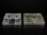 VIDROS, dois (2) tinteiros confeccionados em vidro translucido, moldagem quadrangular, sendo: A) 1 translucido com 2 recipientes sem tampa, medindo 4x17x13cm e B) 1 em tom esverdeado, 3 compartimentos sem tampa, medindo 4x20x14,5cm. Ambas com leves bicados.
