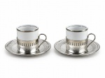 METAL PRATEADO & PORCELANA, duas (2) xícaras para café com seus respectivos pires confeccionadas em metal espessurado a prata com cinzelado em vazados, recipiente interno em porcelana branca da manufatura VERACRUZ com filete prateado, medindo 5,5x6,5x5cm.