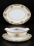 PORCELANA NORITAKE, duas (2) peças confeccionadas em porcelana na tonalidade branca e creme, decorado por elementos florais e vegetalistas em rica policromia com filetes em ouro, sendo: A) 1 travessa oval, medindo 30x22,5cm e B) 1 molheira fixada ao presentoir, medindo 7,5x23,5x15,5cm.