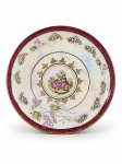 PORCELANA REAL, um (1) prato decorativo confeccionado em porcelana na tonalidade branca com esmaltagem furtacor, decorada por elementos florais e vegetalistas em ouro, espessa faixa na tonalidade vinho, centro reservando cena galante em policromia com pequenas falhas, apresentando falhas na douração, medindo 25,5cm.