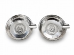 METAL PRATEADO, dois (2) cinzeiros em metal espessurado a prata da marca BEL PRATA, de formato circular, com bordas marteladas e apoio lateral para cigarro, apresentando ao centro moeda antiga brasileira de 1907 da República dos Estados Unidos do Brasil, medindo 7,5cm de diâmetro, acondicionado em caixa original com marcas do tempo.