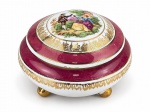 PORCELANA, uma (1) caixa porta joias confeccionada em porcelana na tonalidade branca, decorado por espessas faixas na tonalidade vinho, decorado por elementos vegetalistas e filetes em ouro com centro representando cena musical em policromia, medindo 10x13cm, apresenta pequeno bicado na borda e falhas na douração e pintura.