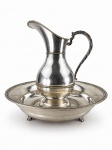 METAL PRATEADO, duas (2) peças: 1 bacia e 1 gomil, confeccionados em metal espessurado a prata da manufatura ART PRATA, decoradas por faixas relevadas com cinzelado de folhagens, corpo, apresentam falhas na prateação, gomil medindo 40,5x35x15,5cm e bacia 13x48,5cm.