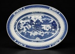 PORCELANA CHINESA, uma (1) travessa oval confeccionada em porcelana oriental na tonalidade branca, decorada por cena com pagodes, elementos florais e vegetaistas, espessas faixas geométricas na técnica BLUE and WHITE, medindo 33x27,5cm.