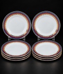 PORCELANA REAL, nove (9) pratos para sobremesa confeccionados em porcelana na tonalidade branca, decorada por faixas na tonalidade azul e vinho, guirlanda floral e filetes em ouro, medindo 19cm. Falhas na douração.