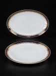 PORCELANA REAL, duas (2) travessas ovais confeccionadas em porcelana na tonalidade branca, decorada por faixas na tonalidade azul e vinho, guirlanda floral e filetes em ouro, medindo 36x24cm e 32x20,5cm. Falhas na douração.