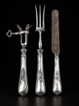 CHRISTOFLE, três (3) peças confeccionadas em metal francês espessurado a prata, cabo cinzelado por elementos vegetalistas, sendo: A) 1 suporte para osso de pernil, B) 1 garfo trinchante e C) 1 faca para jantar com lâmina em aço carbono. Peças com sinais de uso, vendido no estado da foto.