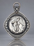 ARTE SACRA, uma (1) medalha de berço confeccionada em metal espessurado a prata, com cena em relevo representando Anjo da Guarda acompanhando uma criança, cercada por moldura ornamentada com friso radial. Parte superior decorada com motivo floral em relevo e argola para suspensão, medindo 8x6,5cm. Falhas na prateação.