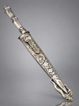 CORNETA (Abramo Eberle, 1896), uma (1) faca dita de GAÚCHA, lâmina em aço inox, possui marca da manufatura CORNETA (uma das pioneiras em cutelaria no Brasil, fundada pelos irmãos Berg, com tradição no ramo desde 1787 na Alemanha, começou as atividades comerciais no Brasil em 1902 e passou a fabricar aqui a partir de 1932, sofreu intervenção em 1943 devido a Segunda Guerra e a partir de 1948 tornou-se 100% nacional), cabo e bainha, confeccionados em metal espessurado a prata com primorosa ornamentação de elementos florais, lâmina com cena de caça, em excelente estado de conservação, medindo 28,5cm de comprimento.