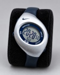 RELÓGIO, um (1) relógio digital da marca NIKE, caixa prateada com pulseira em material emborrachado azul-marinho, visor digital e funções de cronômetro, lap, iluminação e ajuste, resistente à água até 50 metros. Fundo em aço marcado, funcionando, sem garantias futuras, caixa medindo 3,5x4,5cm.