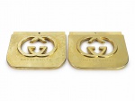 COLECIONISMO, par (2) de alças para bolsa em plástico dourado, com recorte vazado do monograma GG e inscrição GUCCI GUILTY. Peças com furos para fixação, apresentando riscos e sinais de uso. No estado, medindo 17x19cm.