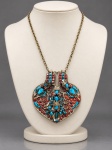 BIJUTERIA TIBETANA, um (1) colar de inspiração tibetana confeccionado em metal prateado, com grande pingente articulado em formato de coração, ricamente ornamentado com aplicações de pedras em turquesa e coral, motivos figurativos e elementos em relevo. Verso igualmente trabalhado, com decoração floral e arabescos, além de cabochões coloridos. Corrente em elos metálicos. Peça de forte caráter étnico e decorativo. No estado, faltando 1 pedra, pingente medindo 10x9,5cm.