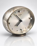 RELÓGIO, um (1) relógio de mesa suíço da marca SWIZA, modelo SWIZA 8, com mecanismo mecânico de 8 dias, caixa circular em metal prateado, mostrador de acabamento acetinado com marcadores aplicados e ponteiros pretos com detalhes dourados. Inscrição SWISS MADE no mostrador. Parte posterior com comandos para corda e ajuste. Peça vintage, apresentando sinais do tempo, oxidação e desgastes no acabamento. No estado, não testado e sem garantia de funcionamento, medindo 8x9x3,5cm.