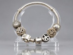 JOIA, uma (1) pulseira PANDORA, confeccionada em PRATA 925, modelo snake chain, com seis berloques decorativos, entre eles símbolo da paz, esferas texturizadas e elementos vazados, medindo 17cm de comprimento aberta e pesando 28,2g.