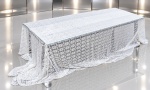CAMA, MESA & BANHO, um (1) grande corte de tecido sintético em renda branca para confecção de cortinas, apresentando trabalho vazado com motivos florais e arabescos ornamentais por toda a extensão. Peça no estado, medindo 420x280cm.