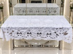 CAMA, MESA & BANHO, uma (1) toalha de mesa retangular confeccionada em tecido na tonalidade branca com rico trabalho floral em rendas e bordados, marcas de guardado e uso, medindo 256x172cm.