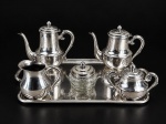 METAL PRATEADO, serviço para chá/café com seis (6) peças confeccionadas em metal espessurado a prata, sendo: A) 1 bule para chá, medindo 18x22x8,5cm, B) 1 bule para café, medindo 19x22x7,5cm, C) 1 açucareiro, medindo 11x15x7cm, D) 1 leiteira, medindo 11x12x7cm, E) 1 manteigueira com recipiente em vidro com ausência do presentoir, medindo 8,5x8,5cm, bicado na borda e F) 1 bandeja retangular, medindo 50x32,5cm. Apresentam falhas na prateação, necessitam banho.