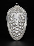 METAL PRATEADO, uma (1) forma para bolo confeccionada em alumínio no formato oval com cacho de uva e folha de parreira em relevo, apresenta mossa na borda, medindo 21x13cm.