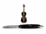 BIJUTERIA e CUTELARIA, lote com duas (2) peças, sendo: A) 1 broche representando violino confeccionado em metal dourado com pintura na tonalidade preta e incrustação de pedrarias translucidas, medindo 6,5cm de comprimento, mossa no grampo e B) 1 canivete dobrável com lâmina em aço marcada COLON INOX, cabo em material sintético preto, apresenta sinais de uso, medindo 11cm.