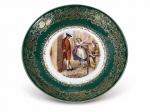 PORCELANA BAVARIA, um (1) prato fundo decorativo confeccionado em porcelana alemã na tonalidade branca, espessa faixa na tonalidade verde com guirlanda floral e vegetalista em ouro, centro com cena galante em policromia, borda filetada a ouro, apresentando falhas na douração, medindo 19,5cm.
