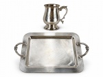 METAL PRATEADO, duas (2) peças confeccionadas em metal espessurado a prata, sendo: A) 1 caneca da manufatura BAND PLATE, corpo bojudo, base escalonada e alça em arabesco vazado, monogramado, falhas na prateação, medindo 13x12x8cm, mossa na borda e B) RIVA, 1 bandeja retangular da manufatura RIVA, liso, alça cilíndrica em vazado com gomos, sinais de uso, medindo 34,5x24,5cm.